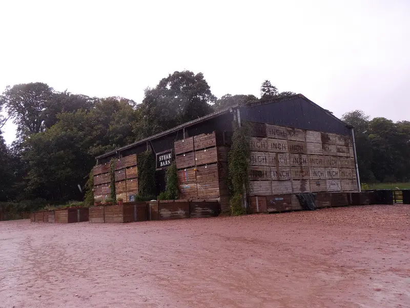 The Steak Barn at Balgove Larder, a farm building faced with stacked wooden crates, beside a gravel yard and trees