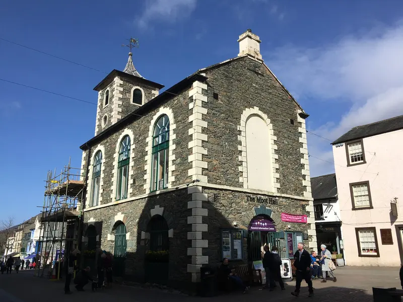 Keswick's slate-built Moot Hall with its white-edged arched windows and small clock tower, in the Market Square under a deep blue sky