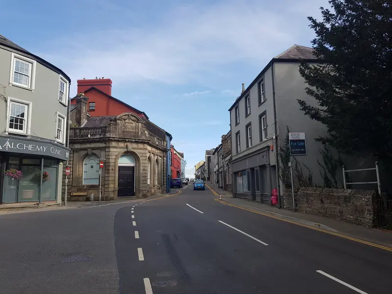 Rhosmaen Street in Llandeilo, a quiet main street of painted Georgian houses and shops curving downhill under a blue sky