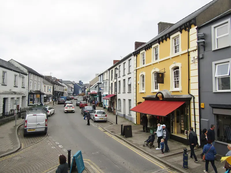 Narberth's High Street lined with colourful painted shops and houses, with shoppers on the pavements and parked cars