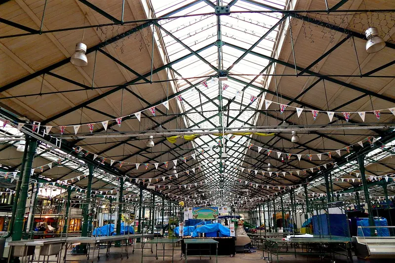 The interior of St George's Market in Belfast, a long Victorian hall with a glazed iron roof, strings of bunting and rows of market stalls
