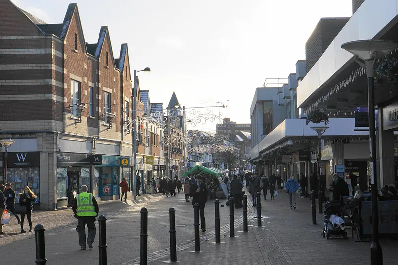 The pedestrianised Parade in Sutton Coldfield in December, with Christmas light decorations strung across the street, a market gazebo and shoppers