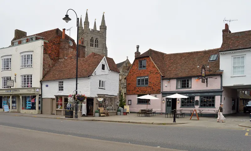 Tenterden's broad High Street lined with old tile-hung and timber-framed buildings, with the tall tower of St Mildred's Church rising behind