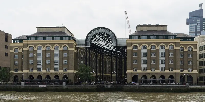 The arched glass roof of Hay's Galleria between two restored brick wharf buildings on the south bank of the Thames, seen from the river
